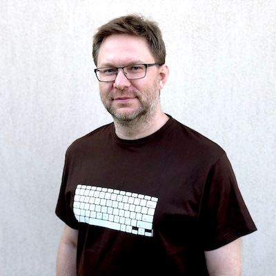Portrait of Pavel Nebeský wearing a black t-shirt with a white keyboard print